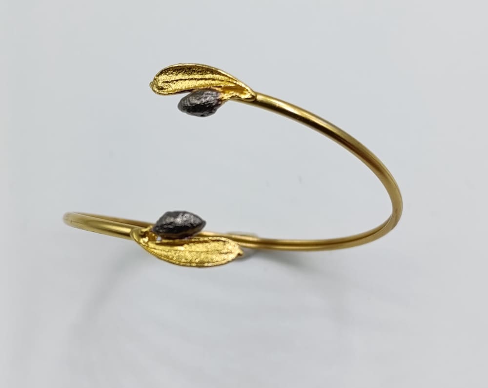 A gold bracelet with leaf-shaped charms on either side of a central loop.