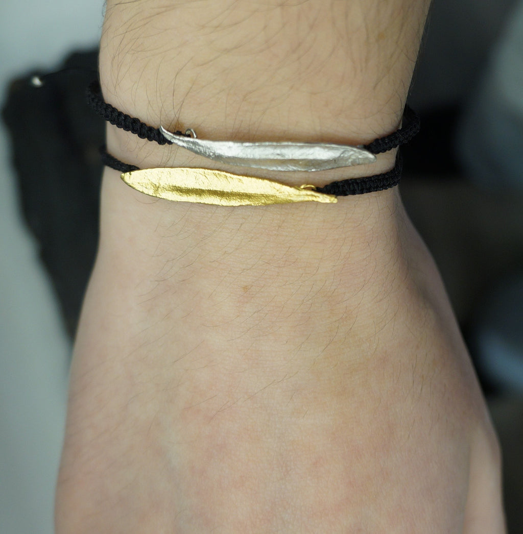 A close-up view of a person's wrist wearing a bracelet with two distinct metal pieces, one silver and one gold.