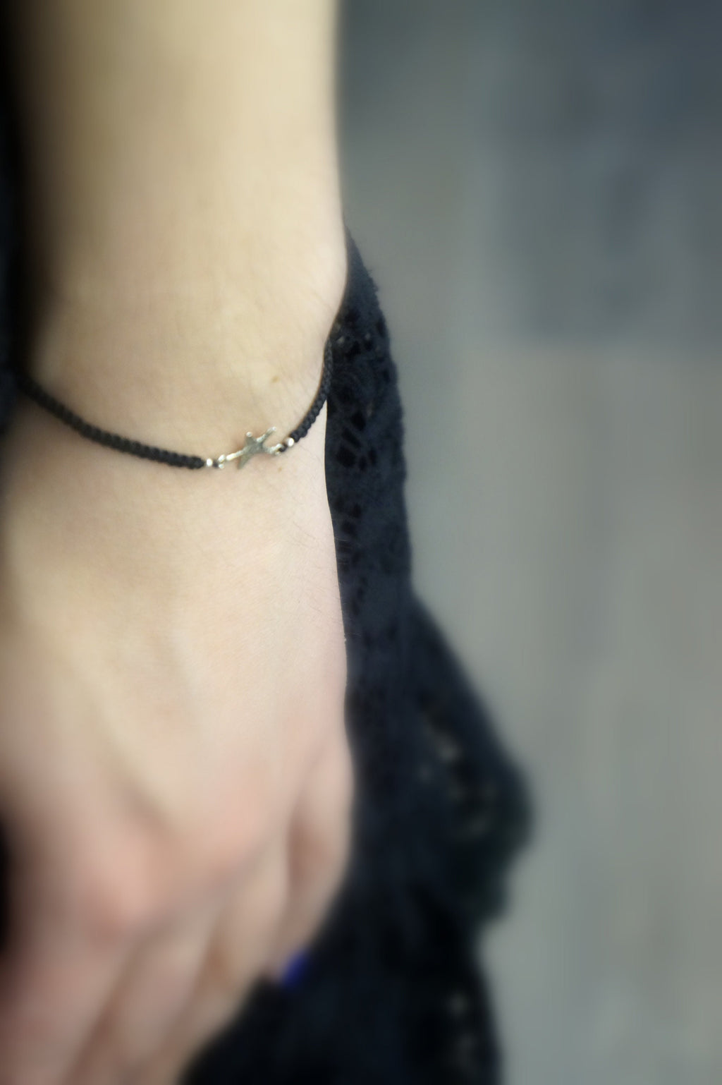 A close-up view of a person's hand wearing a black bracelet with a silver clasp.