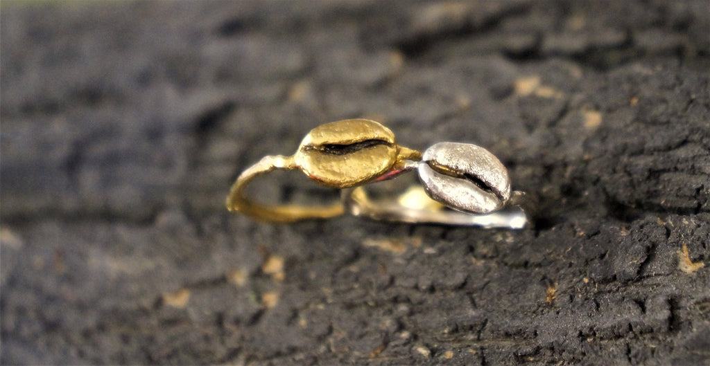 Two rings, one gold and one silver, are placed on a dark, textured surface.