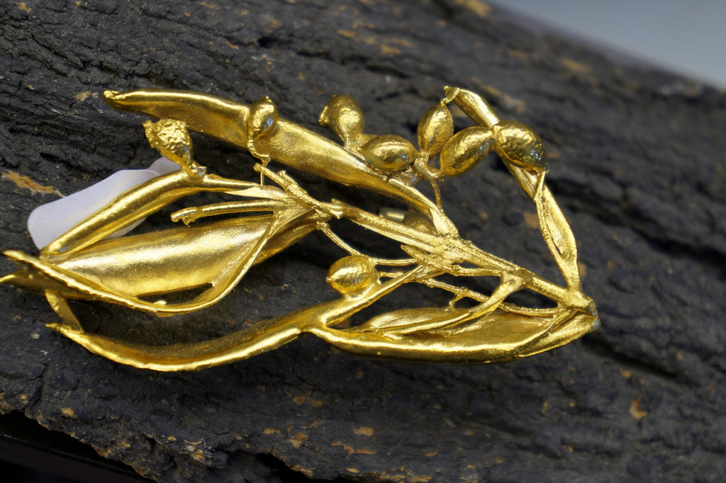 A close-up image of a golden, leaf-like sculpture or ornament with a textured, dark background.