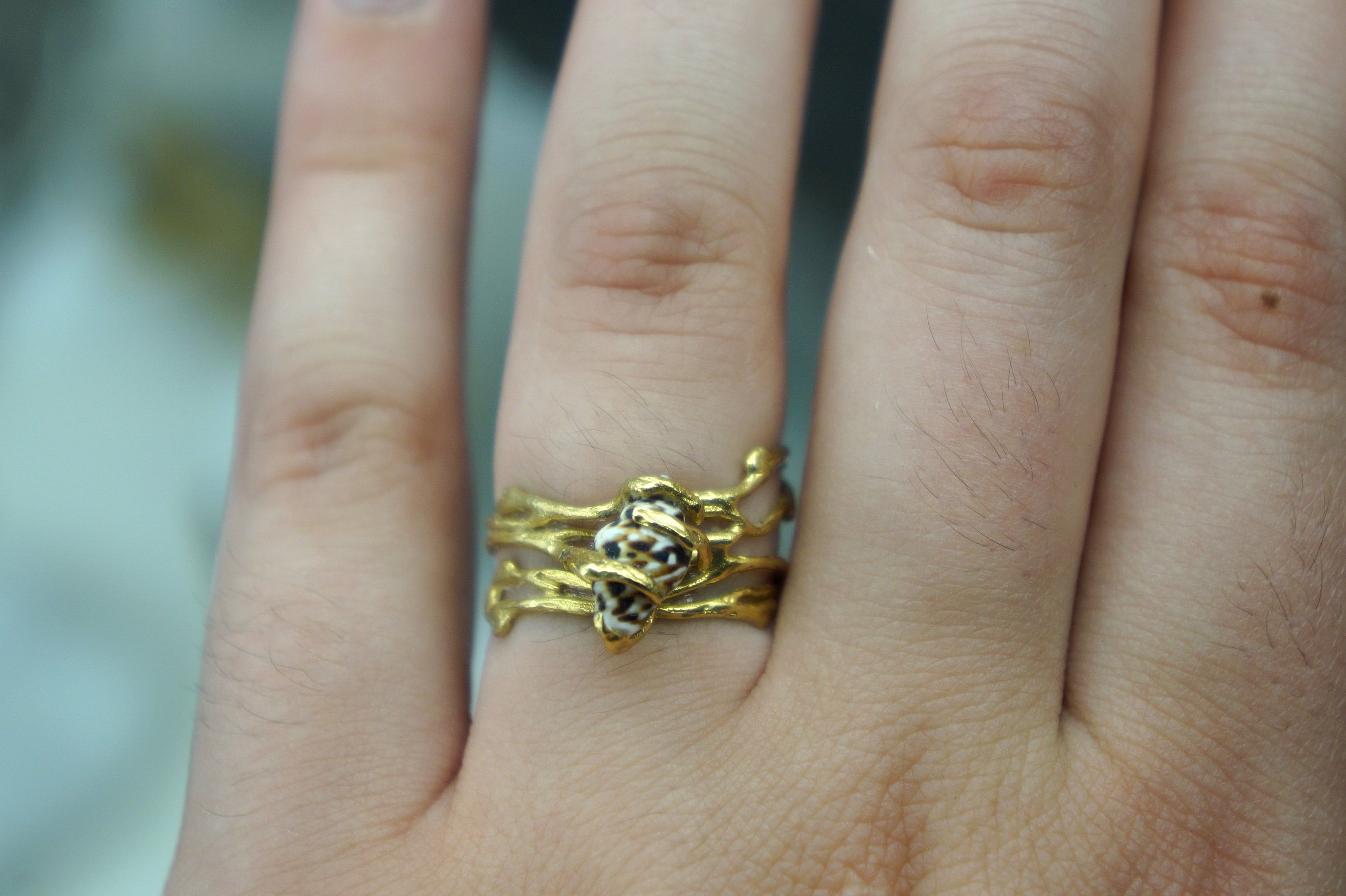 A close-up of a gold ring with a decorative design on the finger.