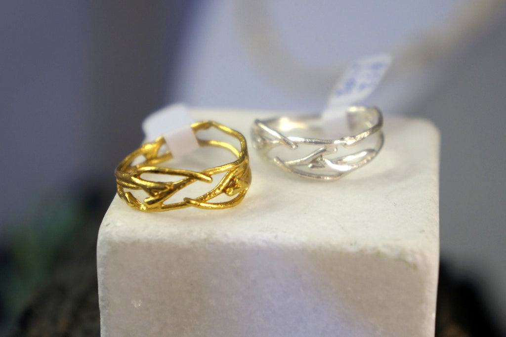 Two rings on display, one gold and one silver, both with intricate designs.