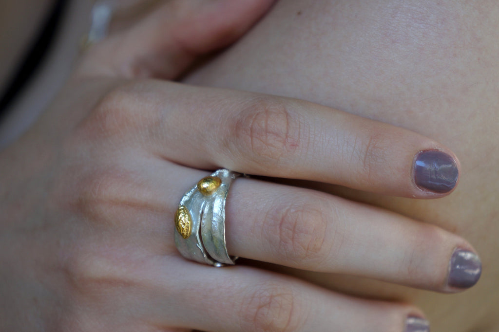 A close-up of a person's hand wearing a silver ring with a unique design.