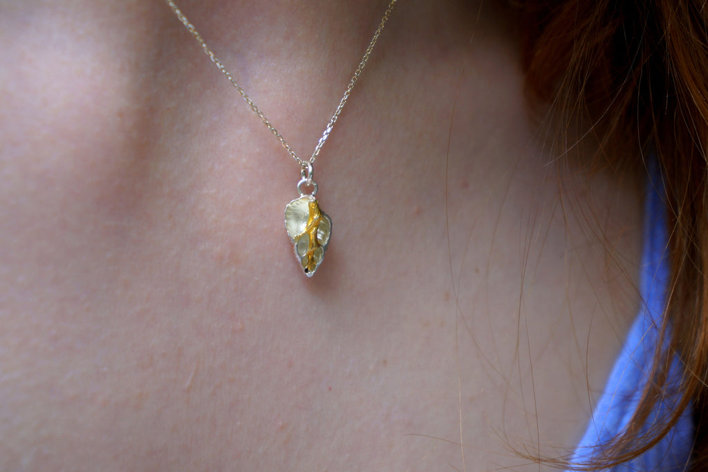 A close-up view of a person's neck and chest area, with a delicate gold-toned pendant necklace visible.