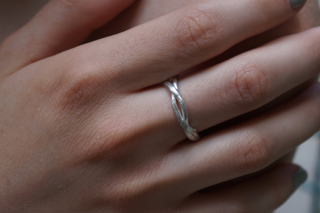 A close-up view of a person's hand wearing a silver ring on the ring finger.