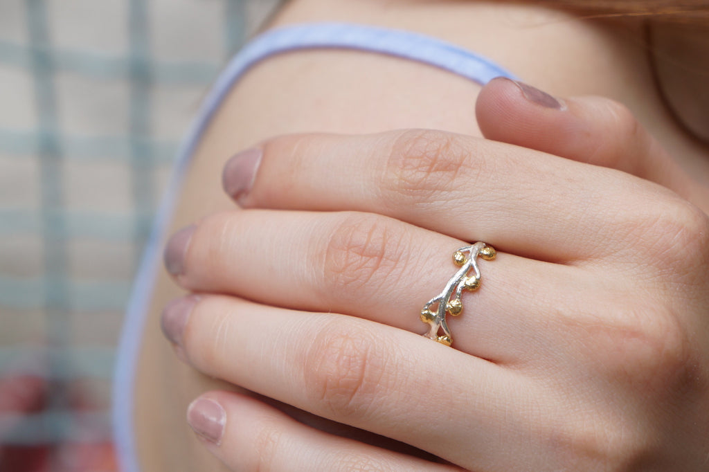 A close-up of a person's hand wearing a ring with a floral design.