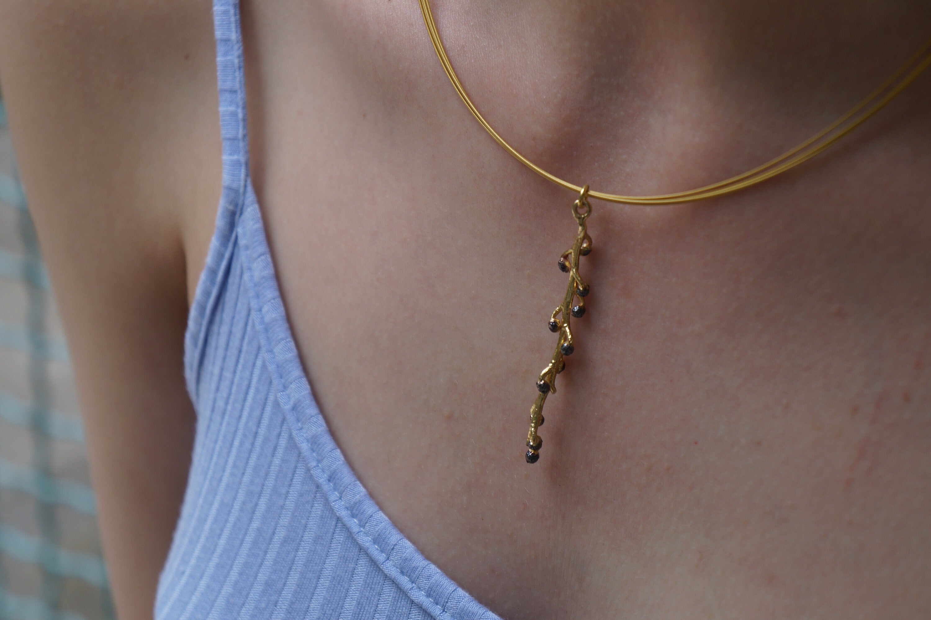 A close-up view of a gold necklace with a pendant featuring small black stones.