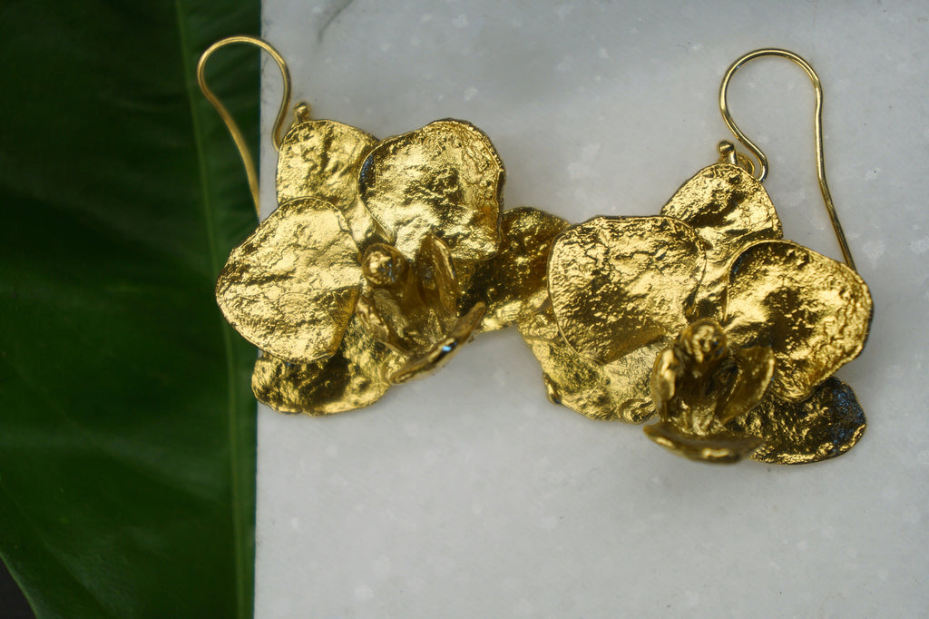 A pair of gold earrings with intricate, textured designs resembling flowers or leaves.