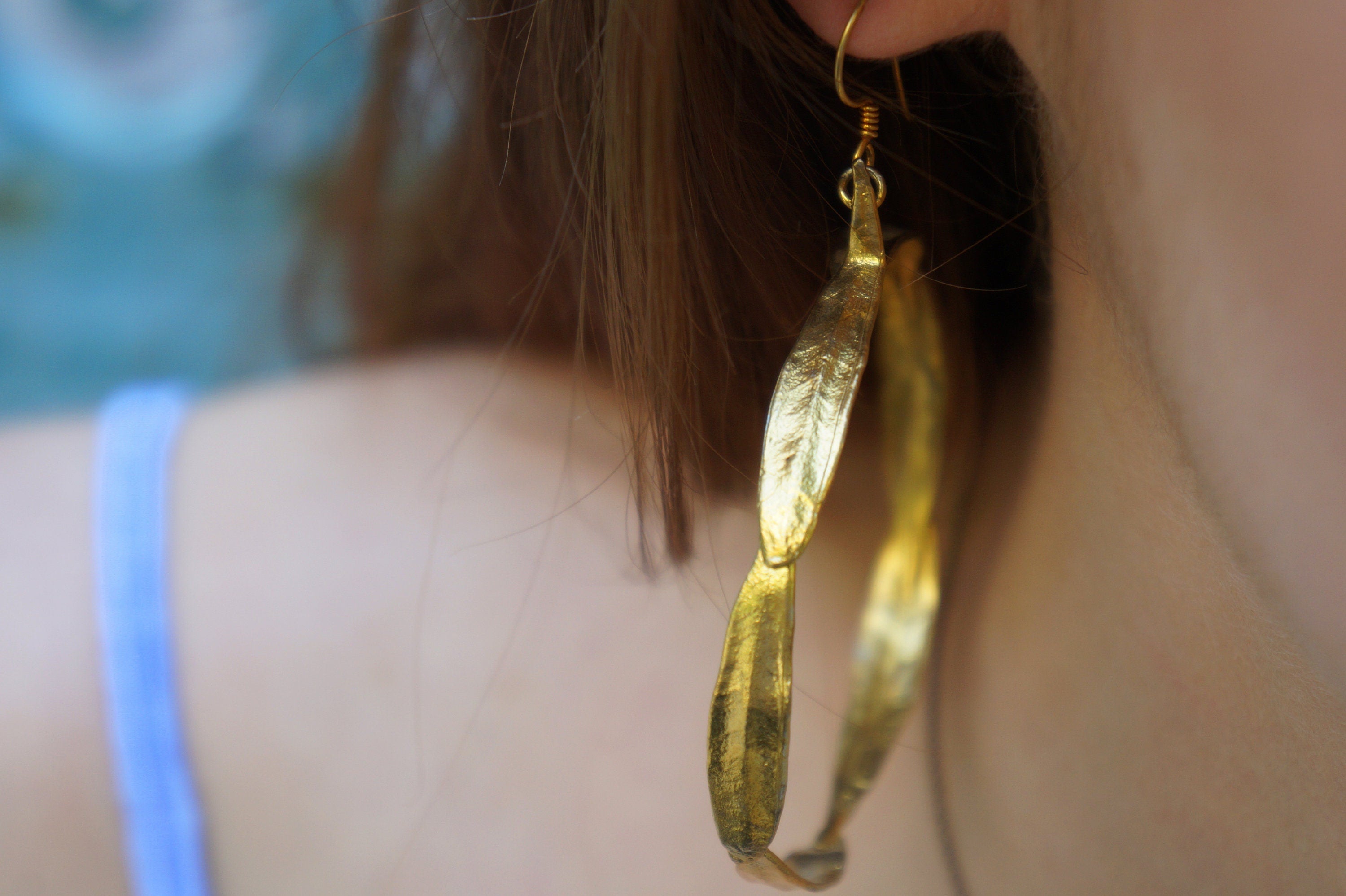 A close-up view of a person's ear adorned with a gold leaf earring.
