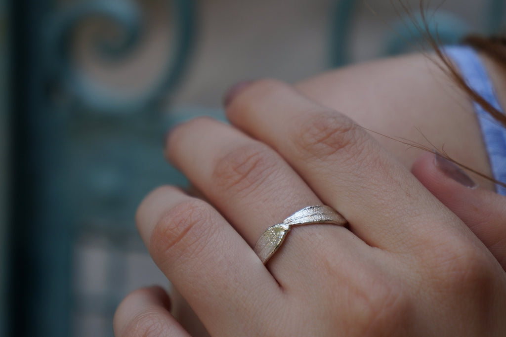 A close-up of a person's hand wearing a silver ring with a diamond.