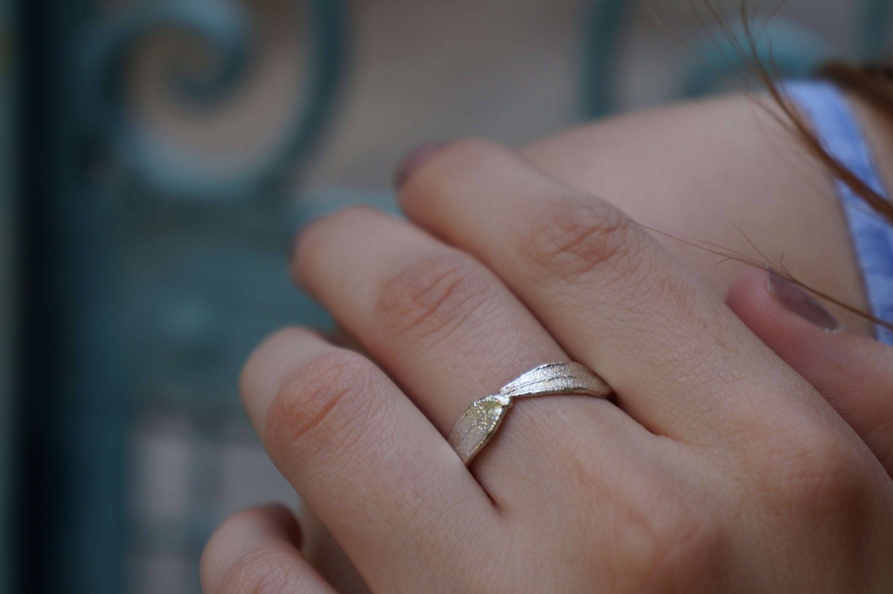 A close-up of a person's hand wearing a silver ring with a diamond.