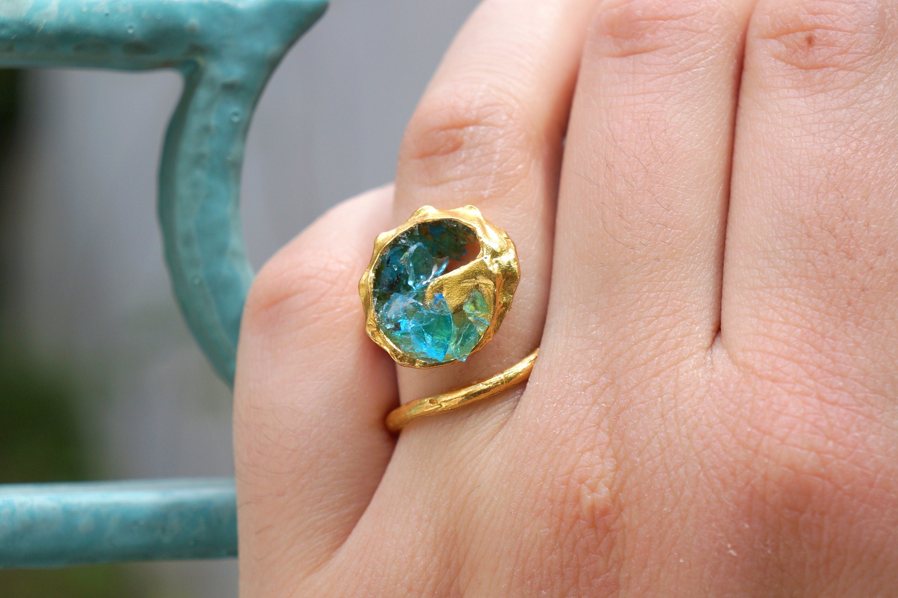 A close-up of a person's hand wearing a gold ring with a blue gemstone.