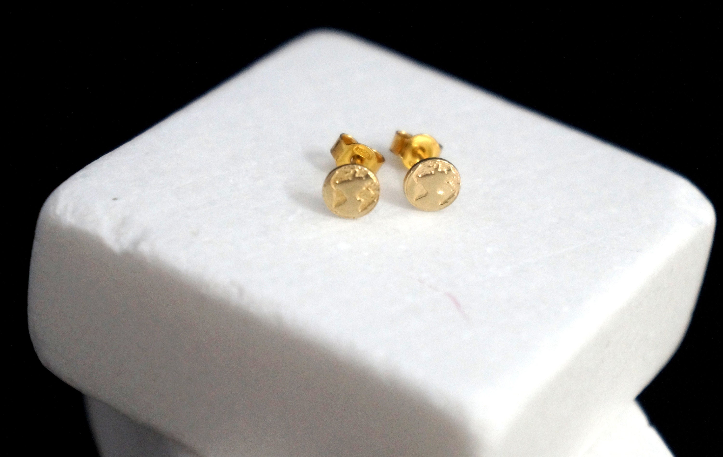 A pair of gold-colored earrings with a star design sits on a white surface.