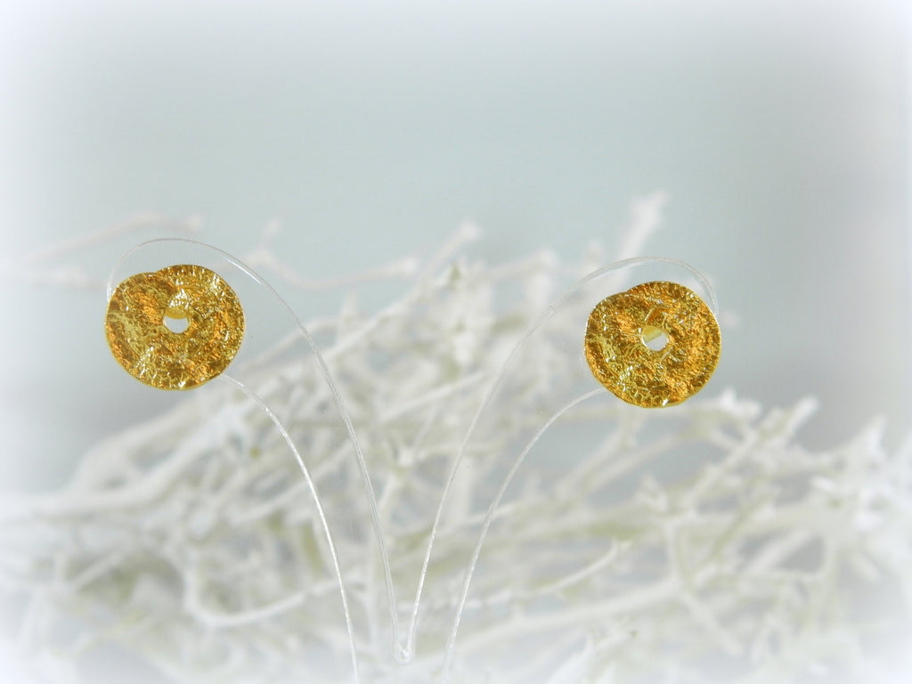 two gold-colored earrings with a textured surface, placed on a white background.