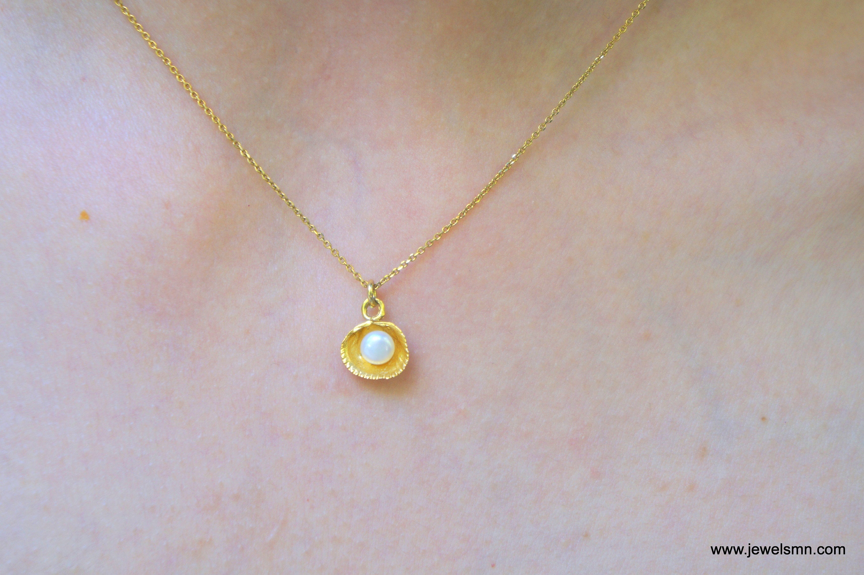 A close-up view of a delicate gold necklace with a small pearl pendant.