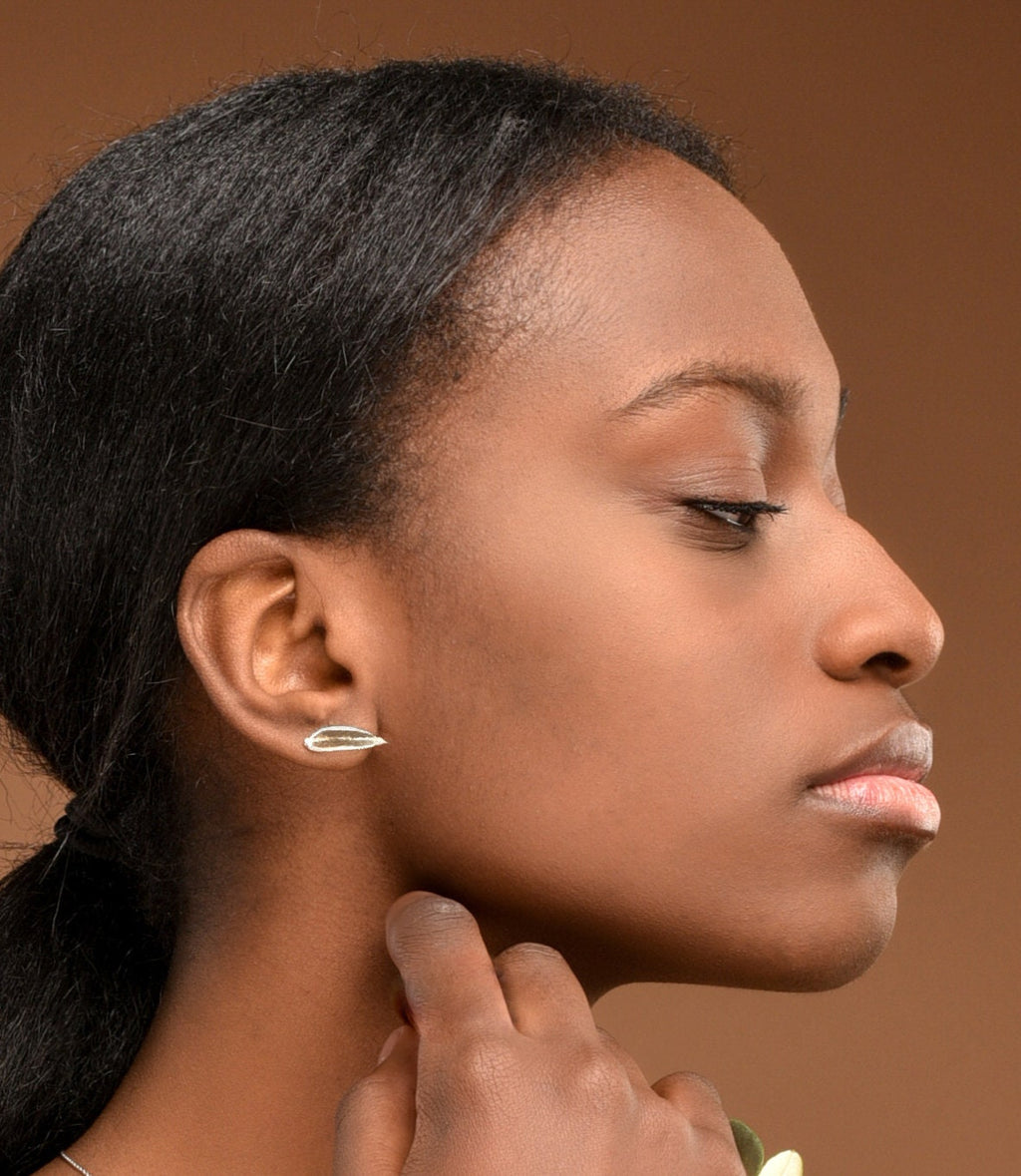 A close-up portrait of a woman with dark hair, wearing a silver earring, looking pensively to the side.