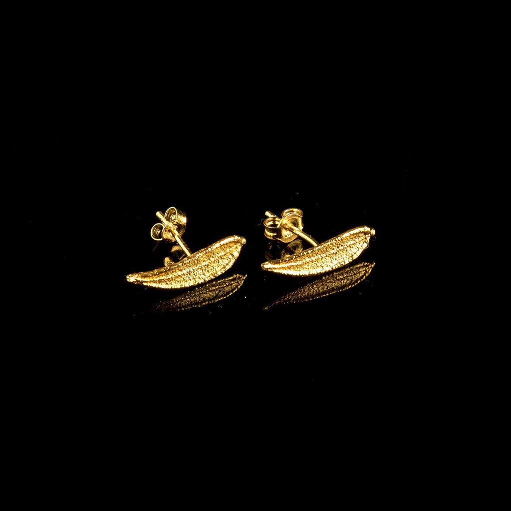 A pair of gold earrings with leaf-shaped designs on a black background.
