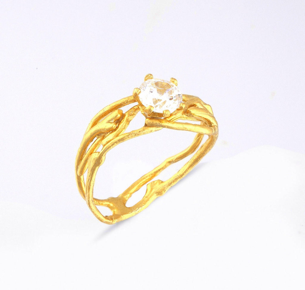 A gold ring with a large central gemstone, possibly a diamond, set in an intricate, organic design.