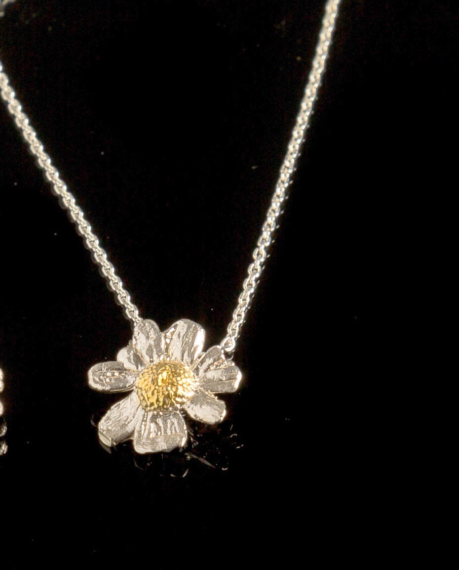 A delicate silver necklace with a pendant featuring a single, intricately designed flower.