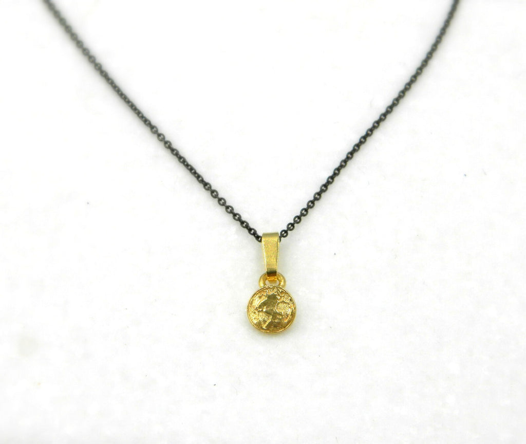 A gold-colored pendant necklace with a black chain.