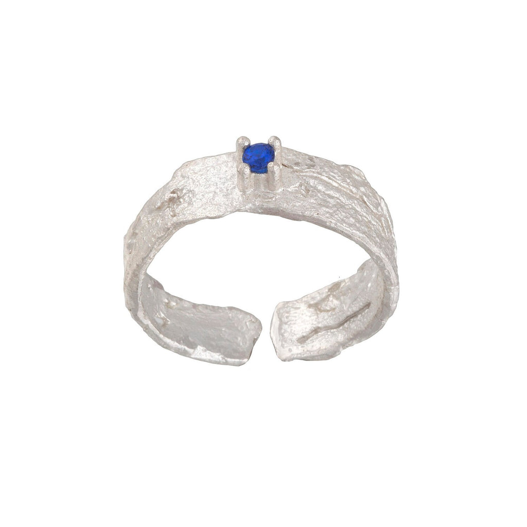 A silver ring with a blue gemstone, possibly a sapphire, set in the center.