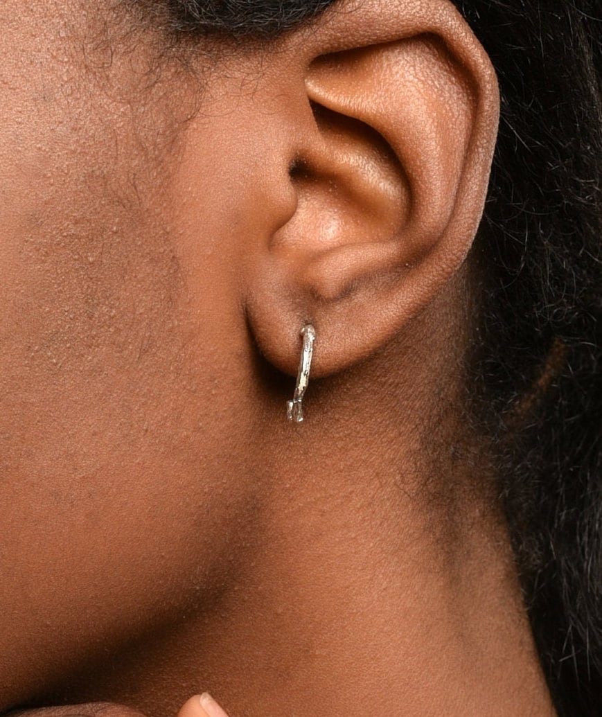 A close-up view of a person's ear with a silver earring.