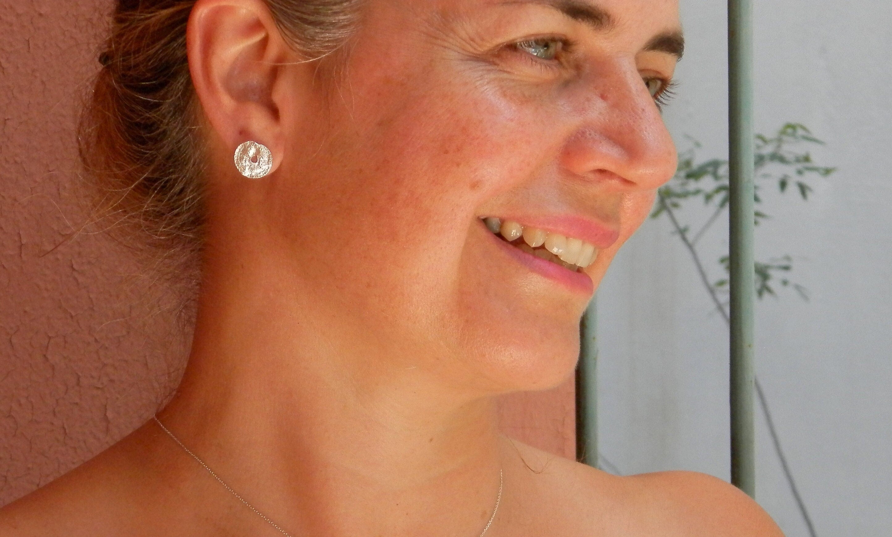 A woman with a bright smile and a silver earring is shown in the image.