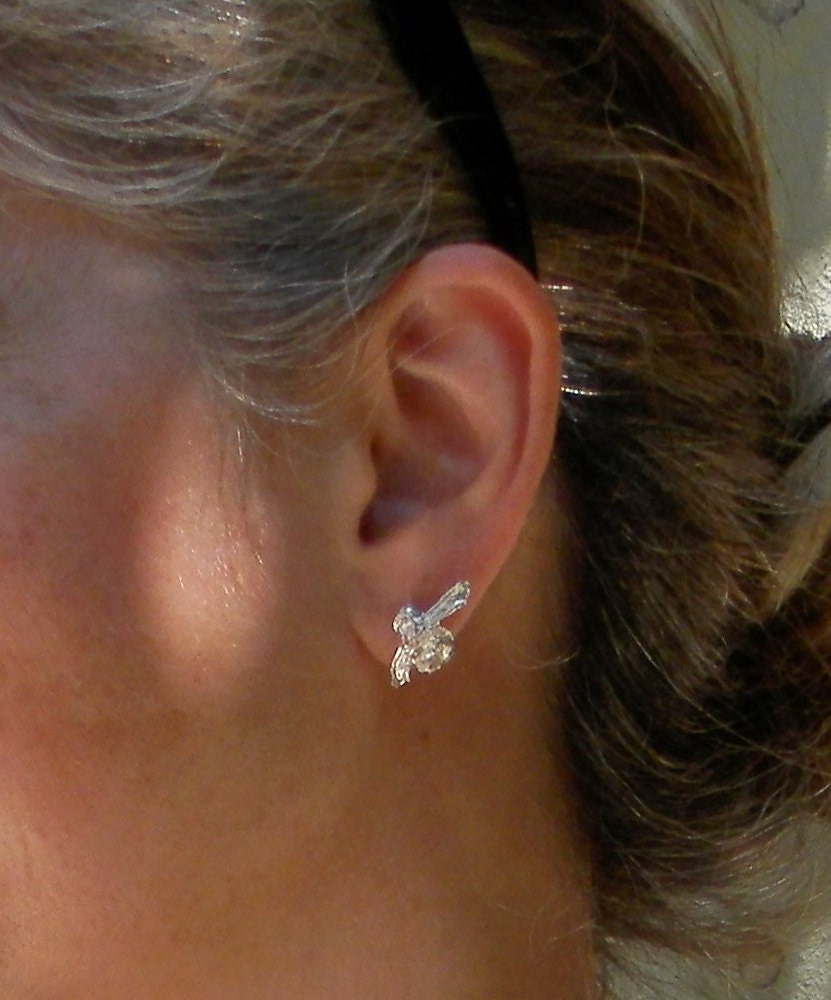 A close-up view of a person's ear adorned with a silver earring featuring a floral design.