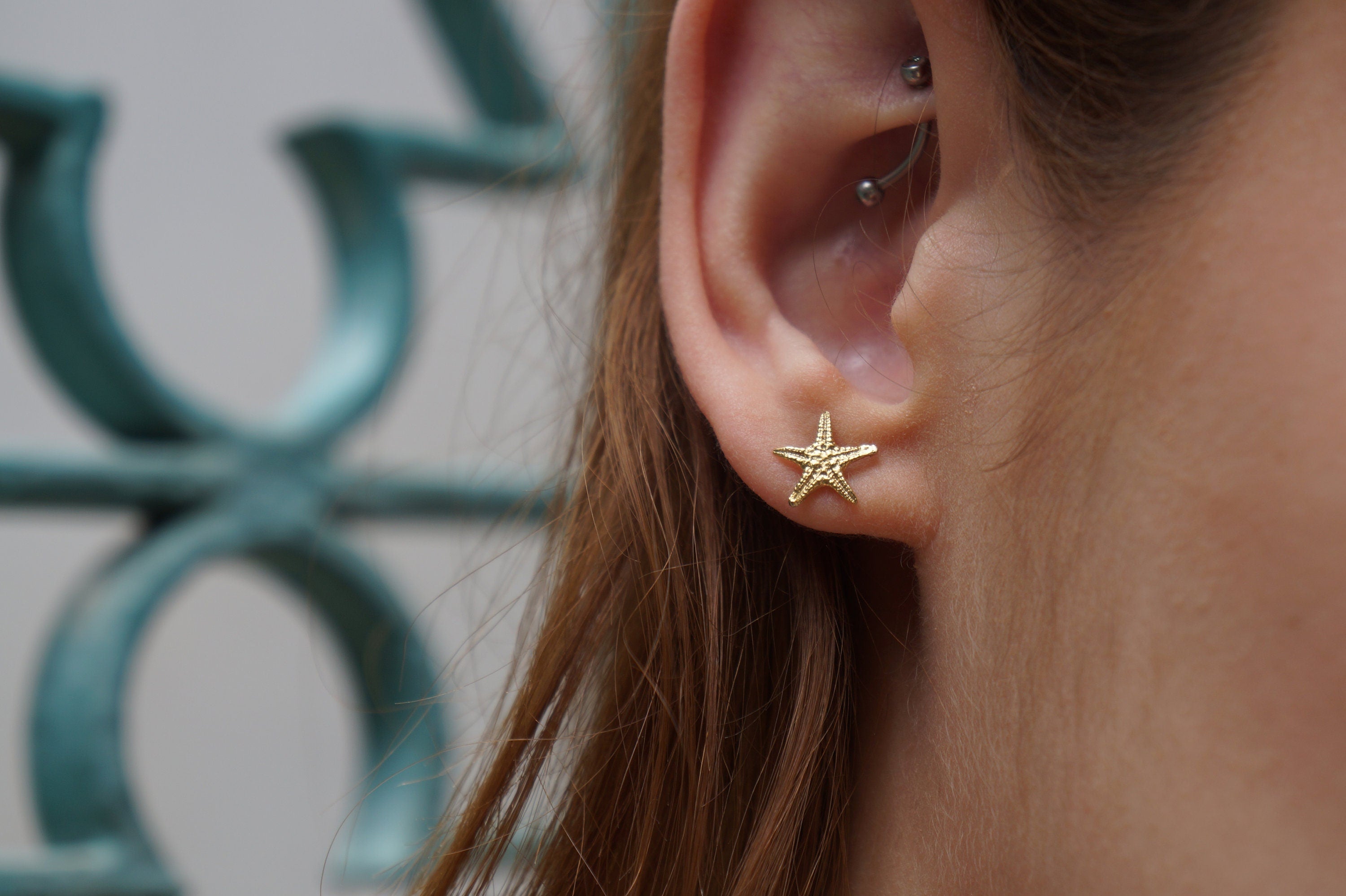 A close-up of a person's ear with a gold starfish earring.