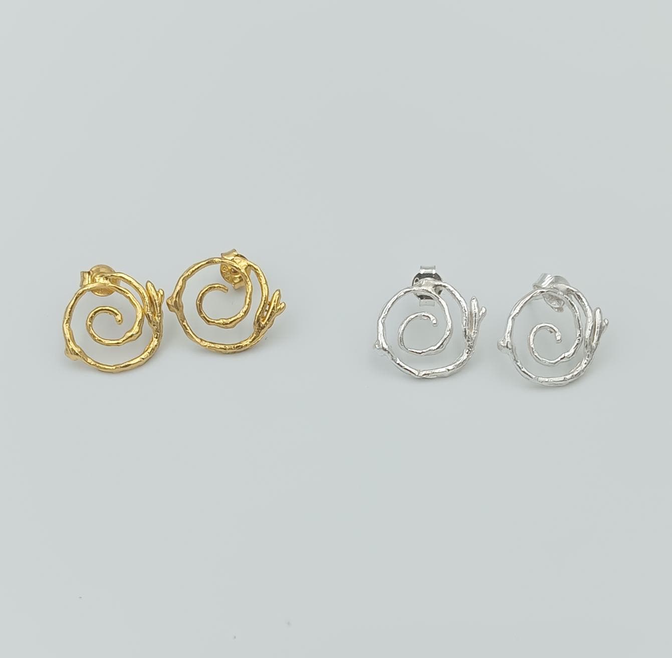 a pair of earrings, each with a unique design, arranged side by side against a light background.
