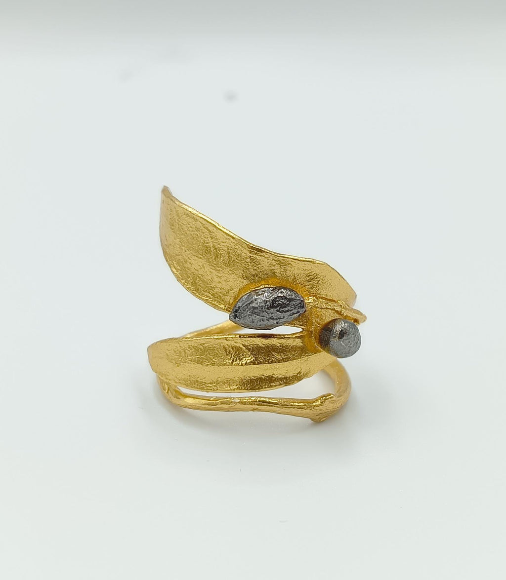 A gold leaf ring with a leaf-like design and two small stones or gemstones on it.