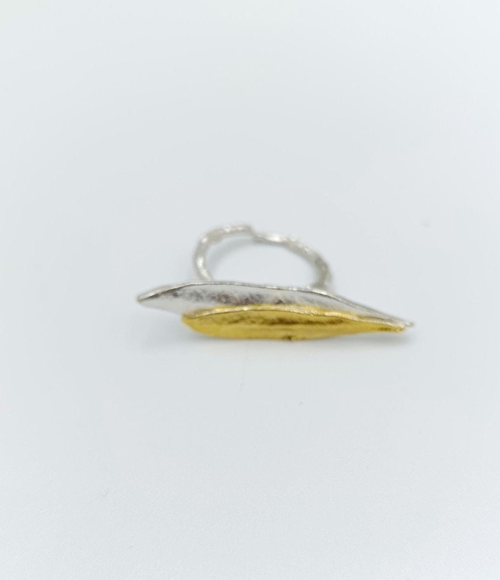A silver and gold ring with a leaf-like design.