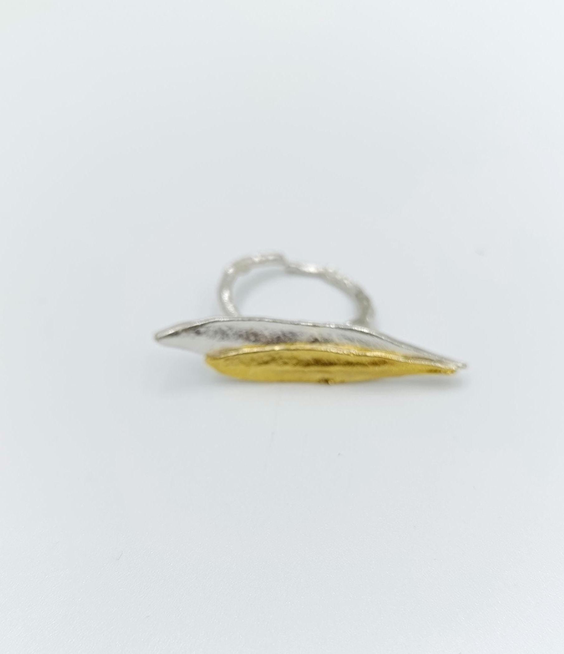 A silver and gold ring with a leaf-like design.
