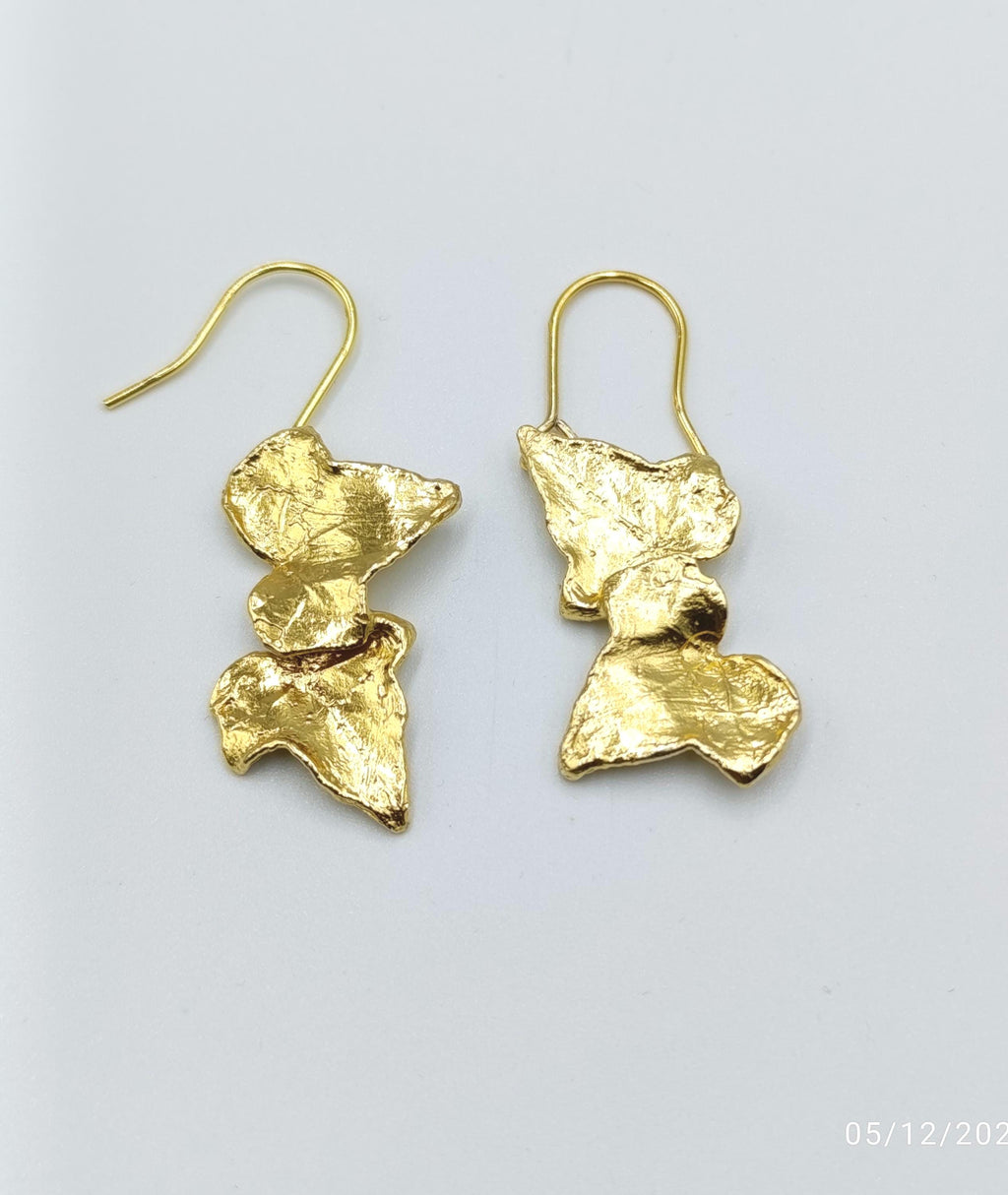 A pair of gold earrings with a unique, organic design.
