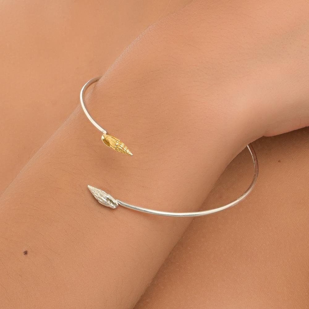A silver and gold bracelet is worn on a person's wrist.