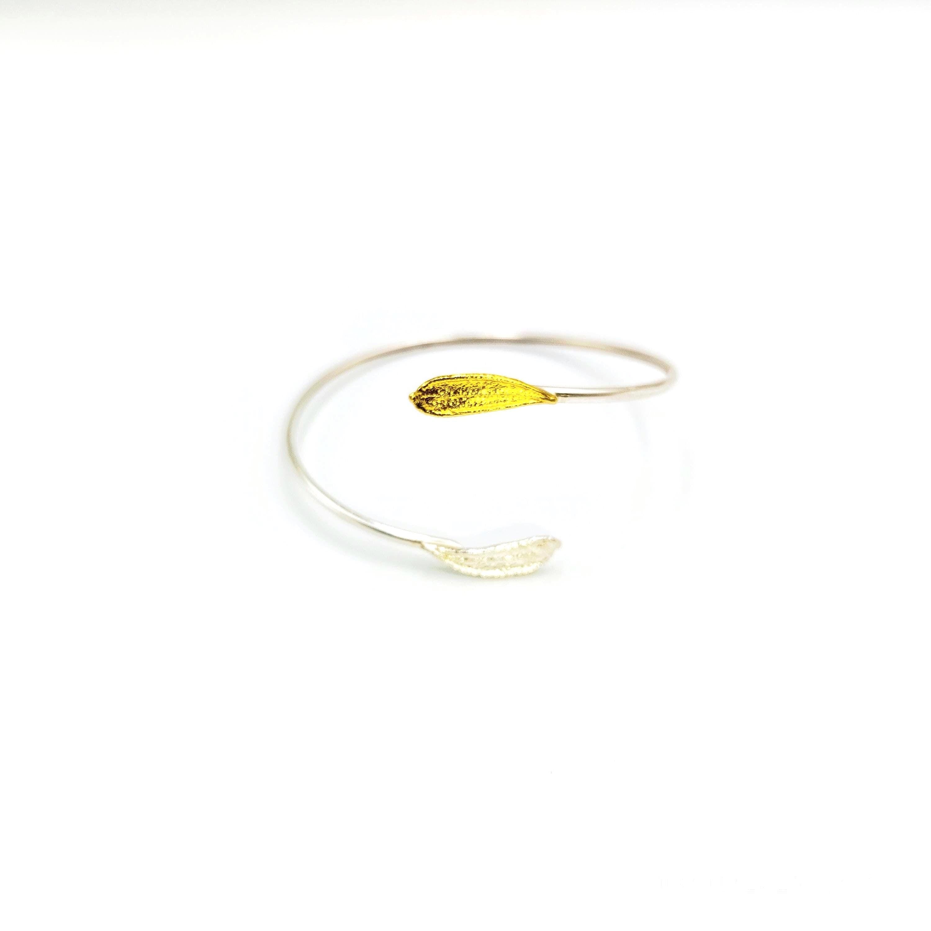 A silver bracelet with a yellow leaf-shaped charm on it.