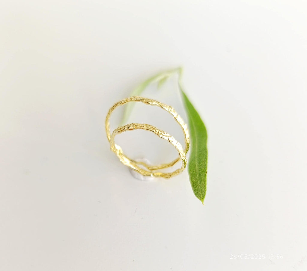 two gold rings with a leaf-like design, placed on a white background.