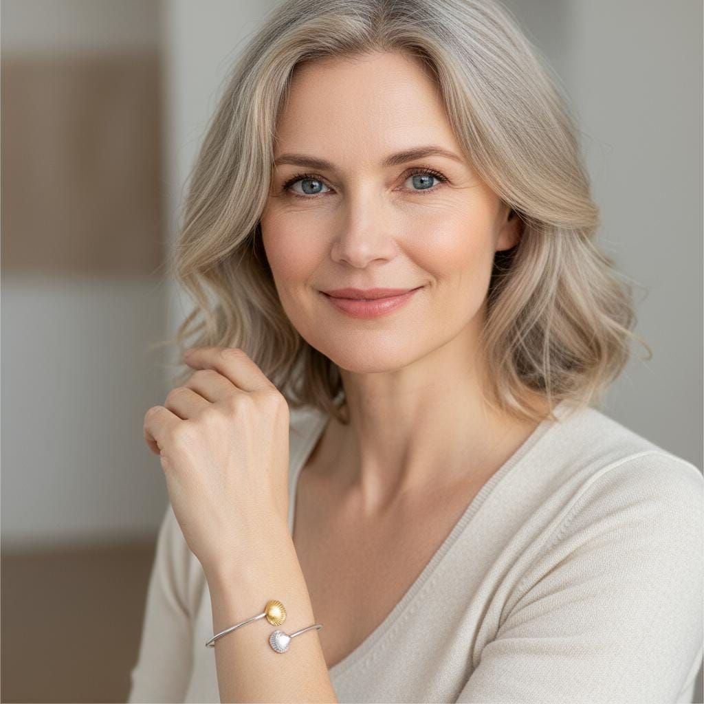 A woman with long, wavy blonde hair is smiling and wearing a bracelet on her wrist.