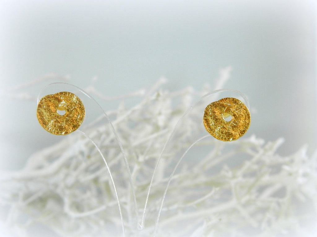 two gold-colored earrings with a textured surface, placed on a white background.