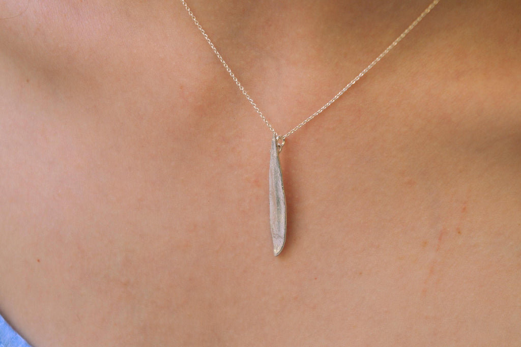 A silver necklace with a pendant is shown in the image.