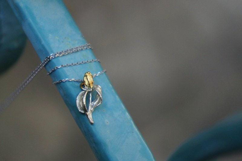 A delicate silver necklace with a pendant is draped around a blue pole, creating an elegant and eye-catching display.