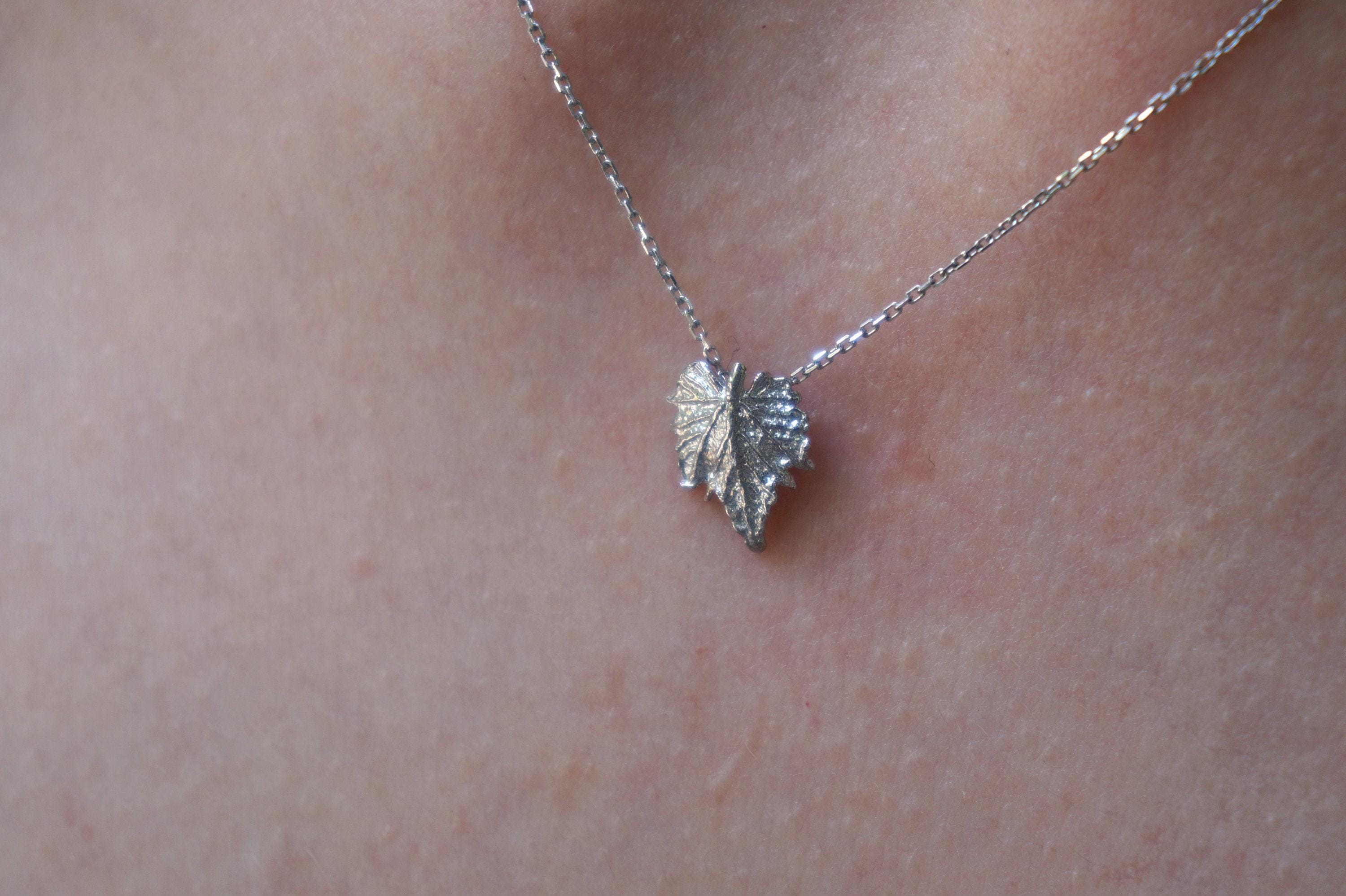 A delicate silver heart-shaped pendant necklace is shown against a blurred background.