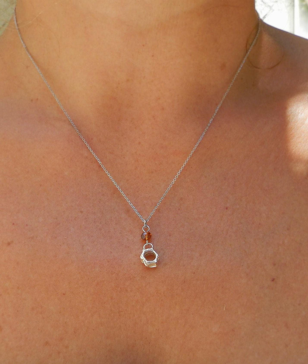 A silver necklace with a small pendant featuring a heart-shaped design.