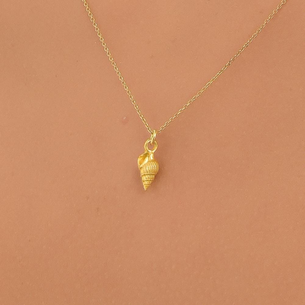 A delicate gold necklace with a small pendant featuring a shell design.