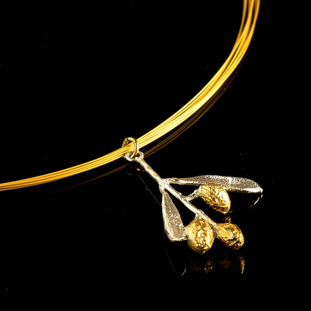 A gold-colored pendant with a branch-like design and three small golden balls is displayed against a black background.