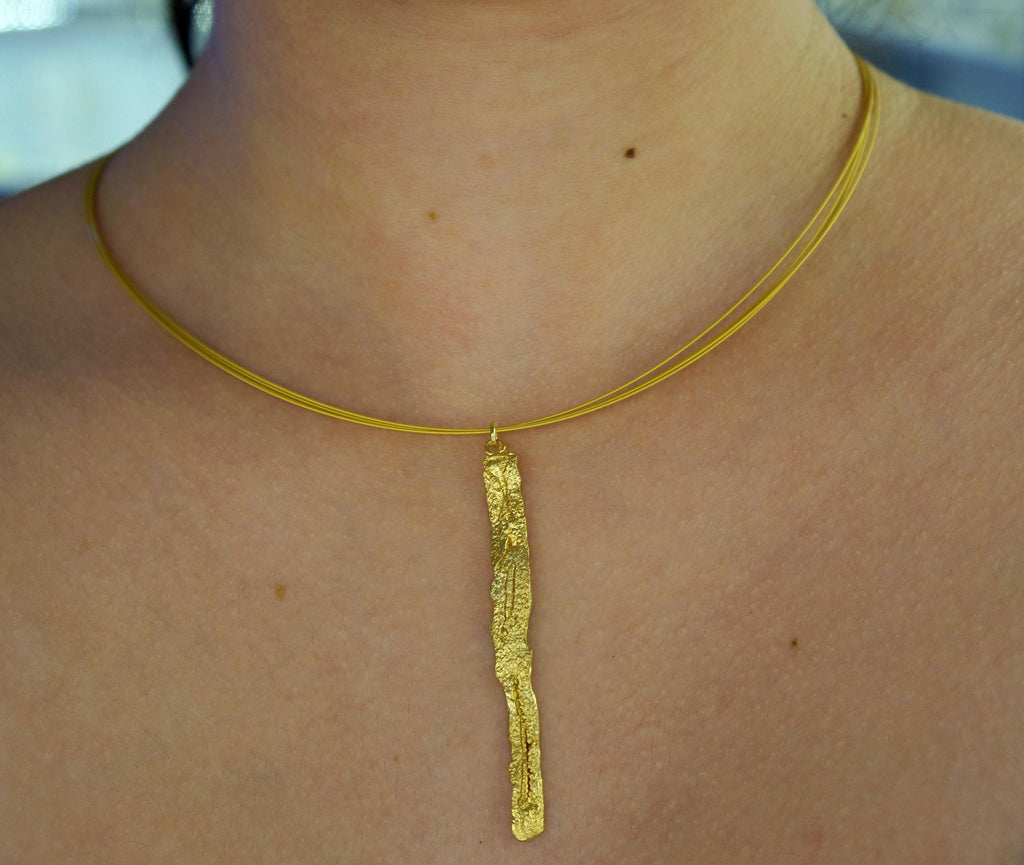 A close-up view of a gold necklace with a pendant hanging from a thin gold chain.