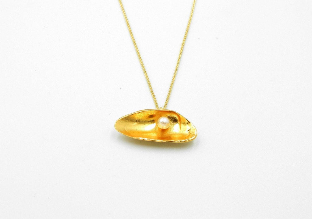 A gold necklace with a pendant in the shape of a shell, containing a single pearl.