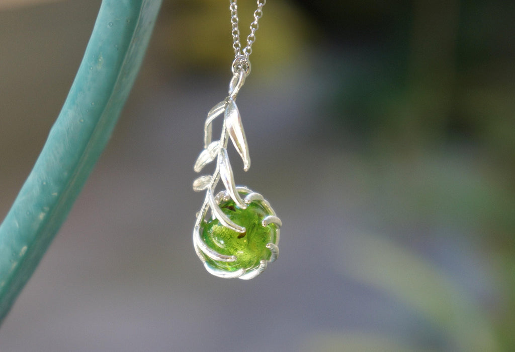 A silver necklace with a green gemstone pendant is shown in the image.