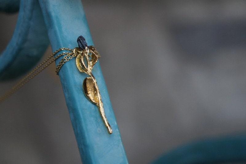 A gold-colored pendant with a blue gemstone is attached to a blue railing.